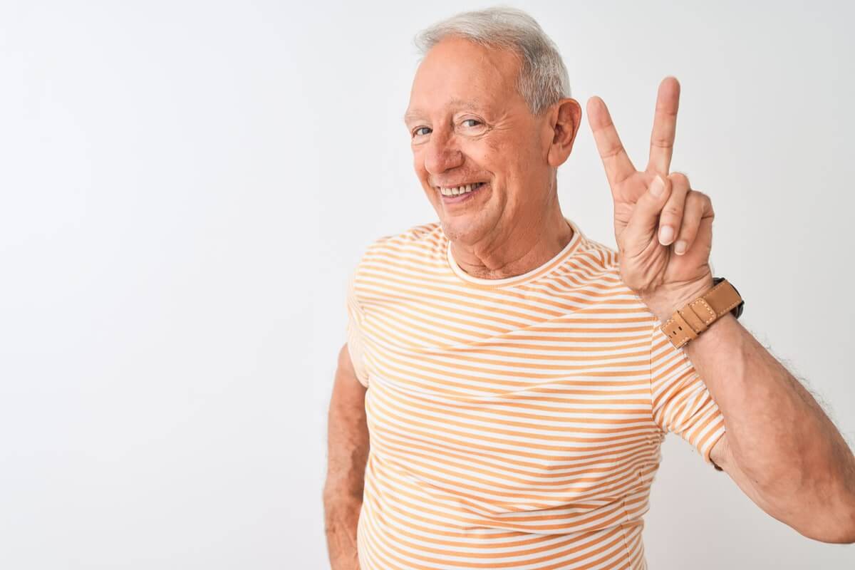 Keeping his partial denture - Senior grey-haired man showing fingers doing victory sign